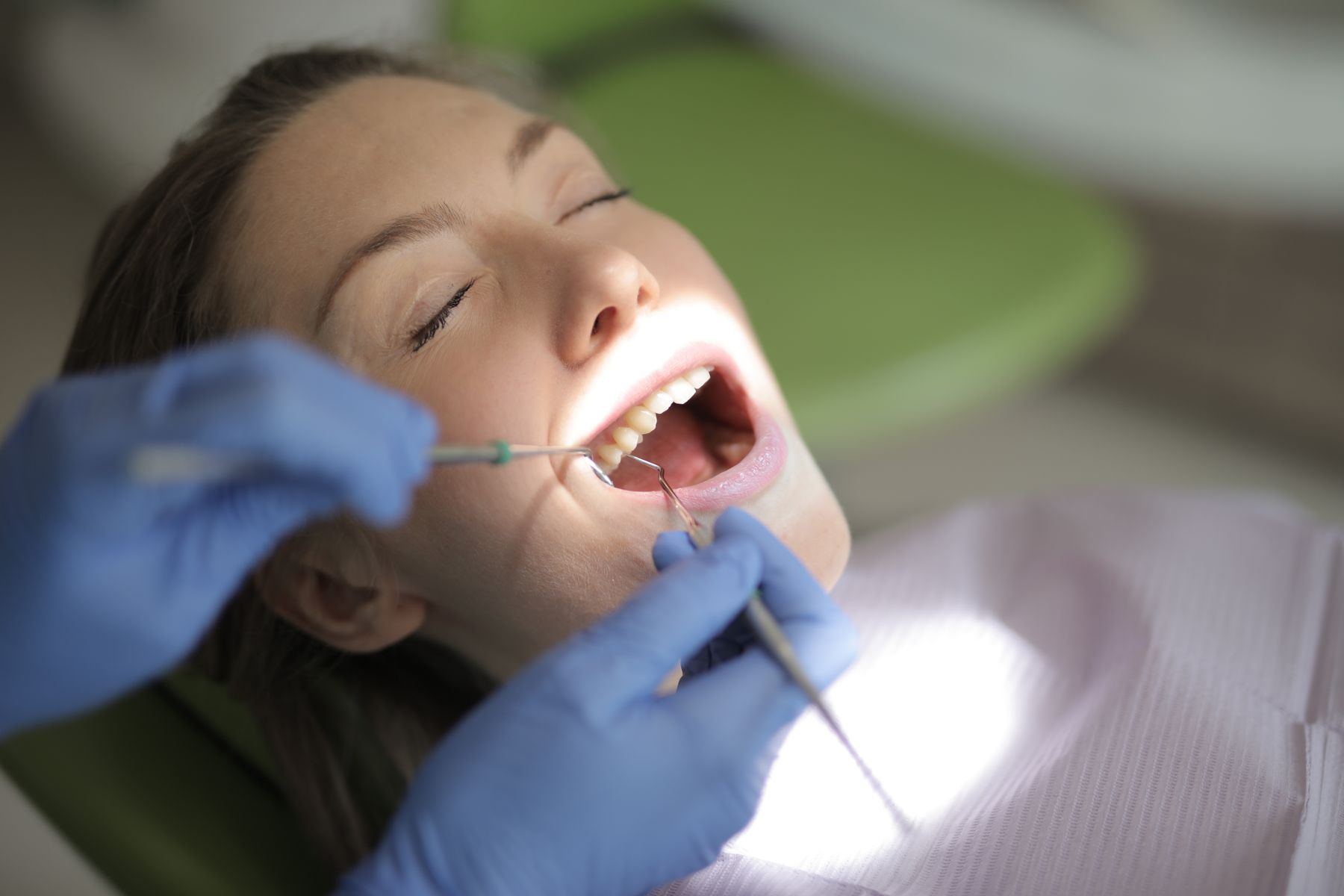 Praticienne de SADENTUS examinant les dents d'un patient au fauteuil dentaire